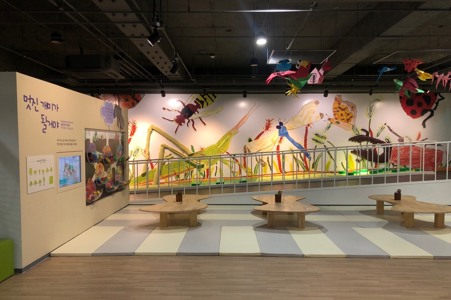 Seoul Urban Life Museum 2 : An exhibition hall for children with several wooden tables and wall painting of different insects 

